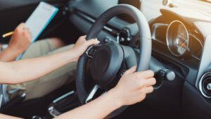 woman practice driving car exam driver licence control steering wheel education and learn on street road by driving instructor teaching at school drive transportation safety travel, people lifestyle
